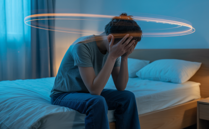 Mein Kopf hört nicht auf zu denken. Erschöpfte Person sitzt nachts auf einem Bett und hält nachdenklich den Kopf, während Lichtspuren das Gefühl von Grübeln und kreisenden Gedanken darstellen.