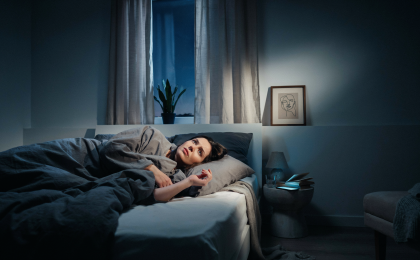 Stress und Schlafstörungen. Person mit Schlafproblemen liegt nachts wach im Bett, während Stress und innere Unruhe den Schlaf beeinträchtigen.